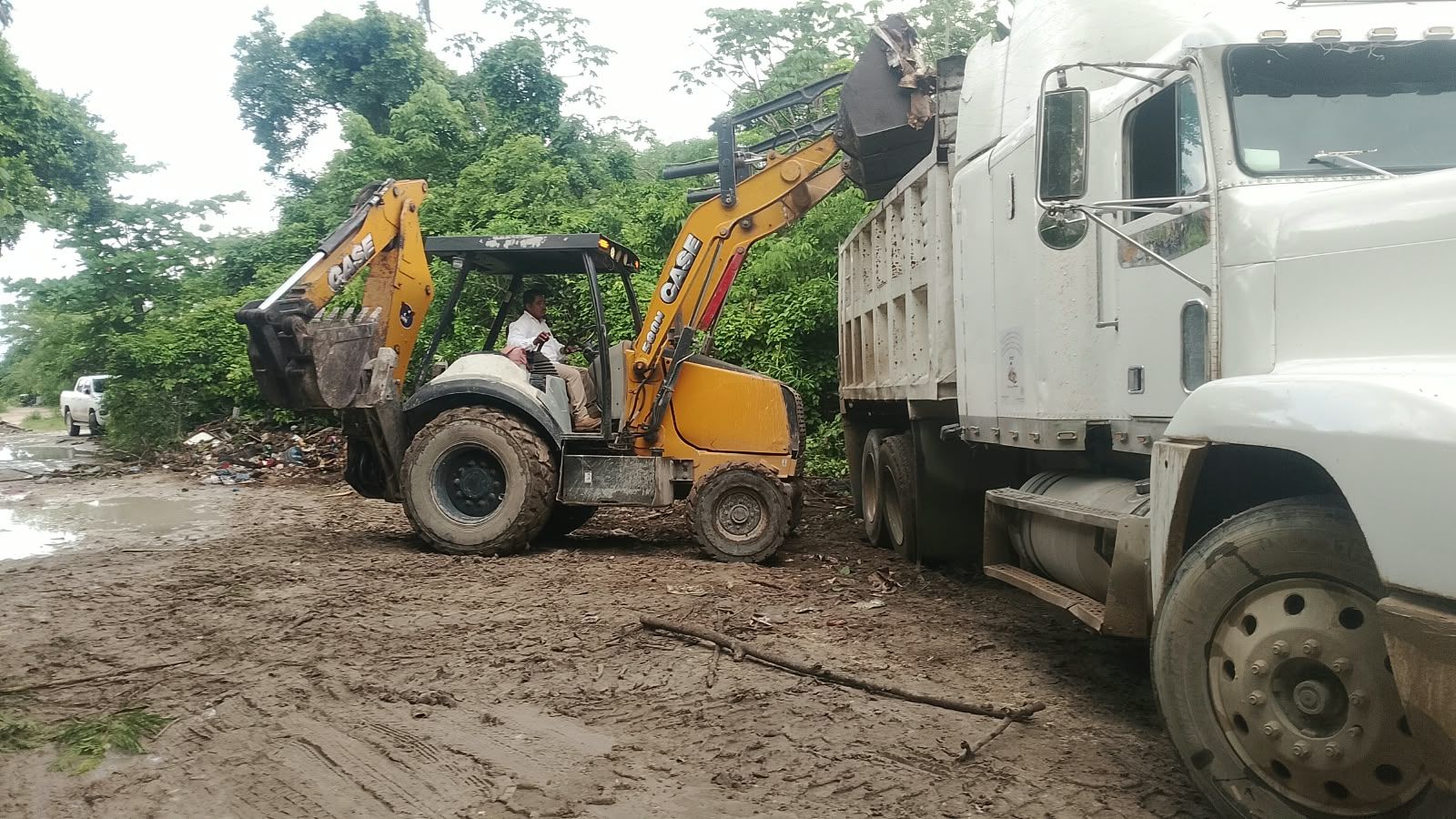 Retroexcavadora cargando residuos en un tractocamión de volteo