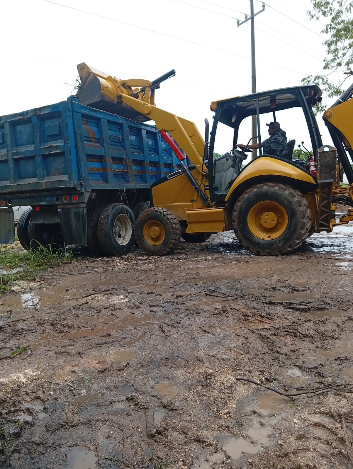 Retroexcavadora cargando material en un camión de volteo